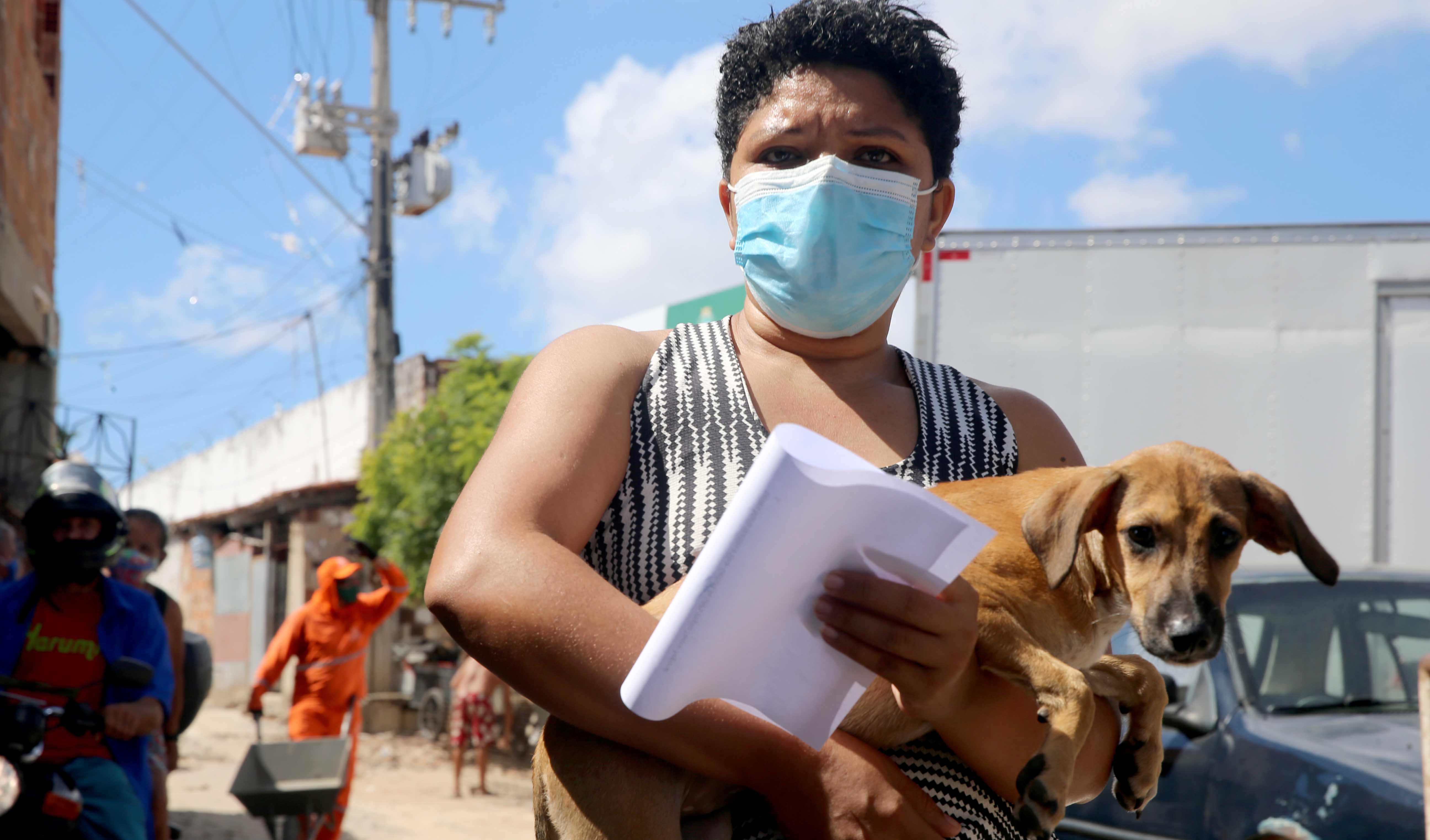 mulher de máscara leva um cachorro no colo